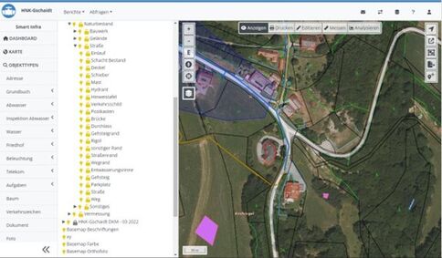 Screenshot eines GIS-Kartenprogramms: Linkes Seitenmenü mit Ordnern, rechts eine Satellitenkarte einer ländlichen Gegend mit Feldern und Straßen. Mehrere farbige Polygonbereiche (violett) markieren Abschnitte; eine kurvige Straße führt durch das Gelände.