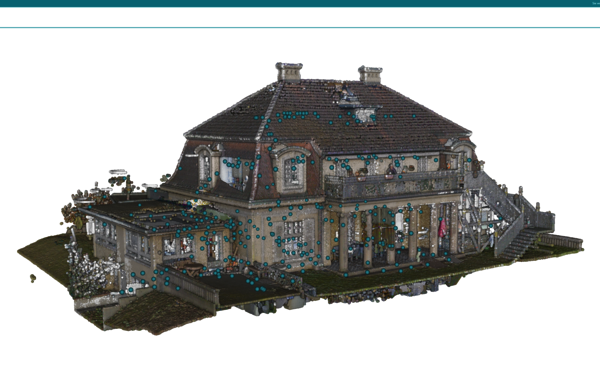 Ein historisches, zweistöckiges Haus aus Stein mit dunklem Satteldach, vielen Fenstern und einer umlaufenden Veranda mit Säulen; eine Außentreppe führt zur oberen Etage. Das Gebäude steht auf einem gepflegten Grundstück mit Terrasse.