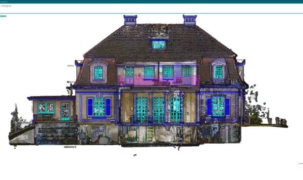 Große Villa mit steilem, mehrstöckigem Dach, zentralem Eingang und vielen Fenstern mit blauen Rahmungen. Die Fassade wirkt gemischt aus Stein und Holz, zweigeschossig mit Dachgauben; das Haus wirkt als prunkvolle klassische Wohnvilla.